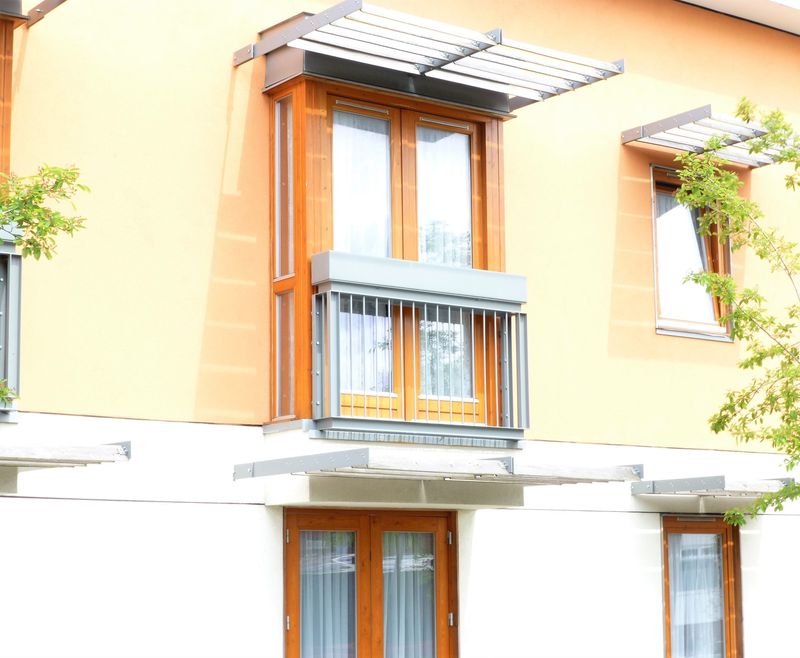 Powder-coated steel Juliet balcony with vertical bars below timber doors
